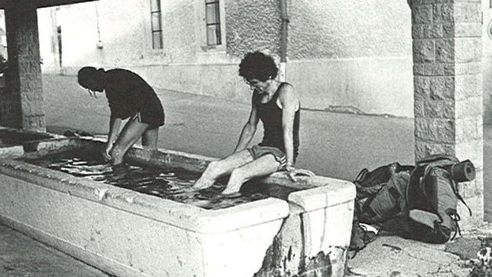 Kurt Saurer und Daniel Bähler tauchen ihre Füsse in einen Brunnen ein.