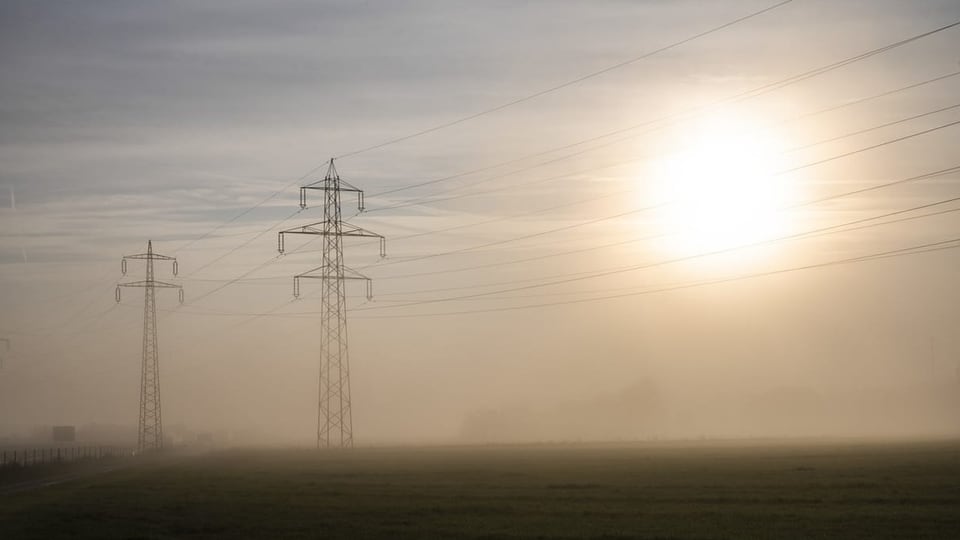 Symbolbild: Strommasten und tiefstehende Sonne imi Nebel.
