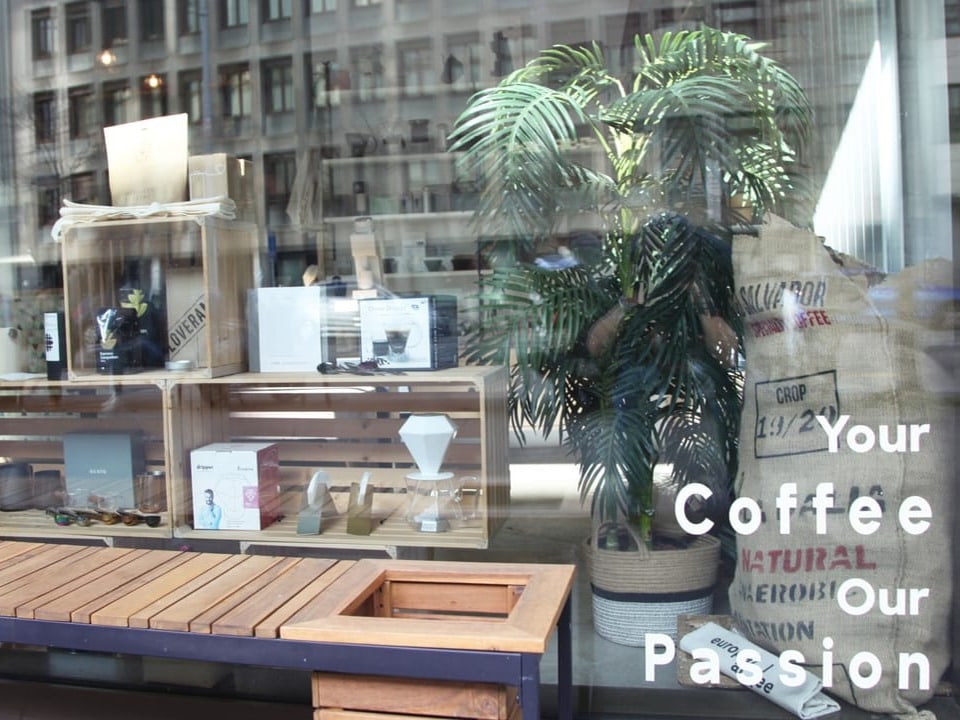 Ein Schaufenster mit der Aufschrift «Your Coffee Our Passion». Präsentiert sind Kaffeezubehör, daneben eine Pflanze.