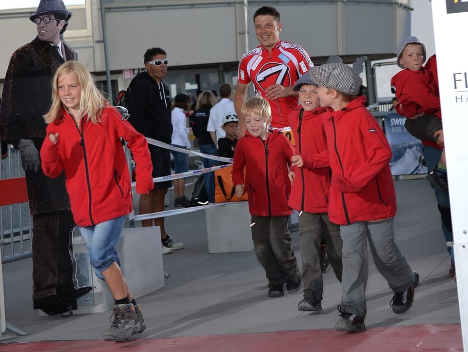 Kinder in roten Jacken rennen über Ziellinie