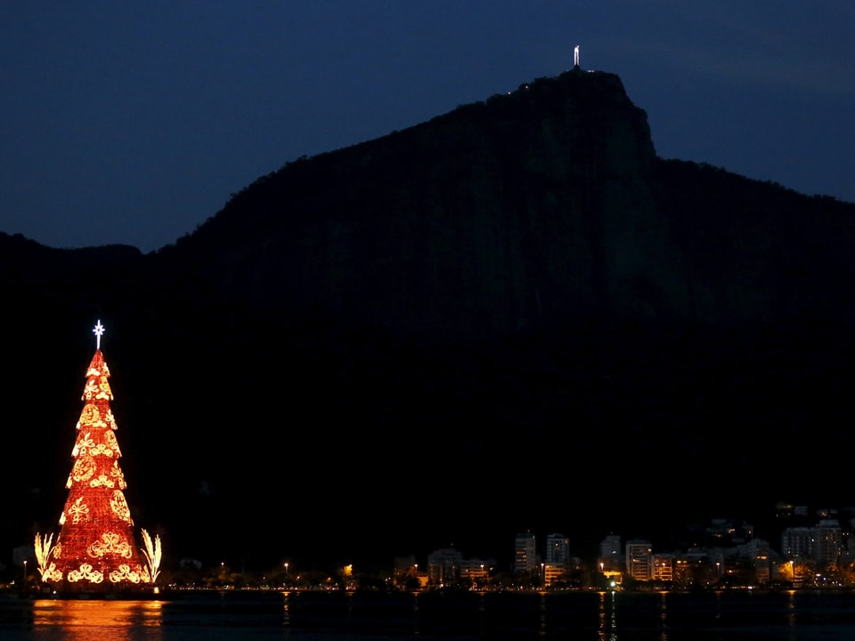 Rotleuchtender, stilistierter Weihnachtsbaum mit goldener Verzierung bei Nacht vor dem Zuckerhut in Rio de Janeiro