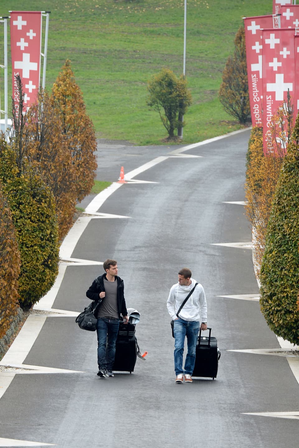 Valentin Stocker und Fabian Frei ziehen ihre Rollkoffer über eine Landstrasse in Feusisberg.