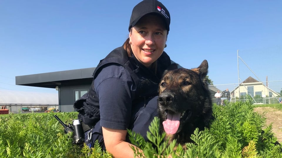 Hundeführerin in Uniform mit Hund im Garten vor der Strafanstalt