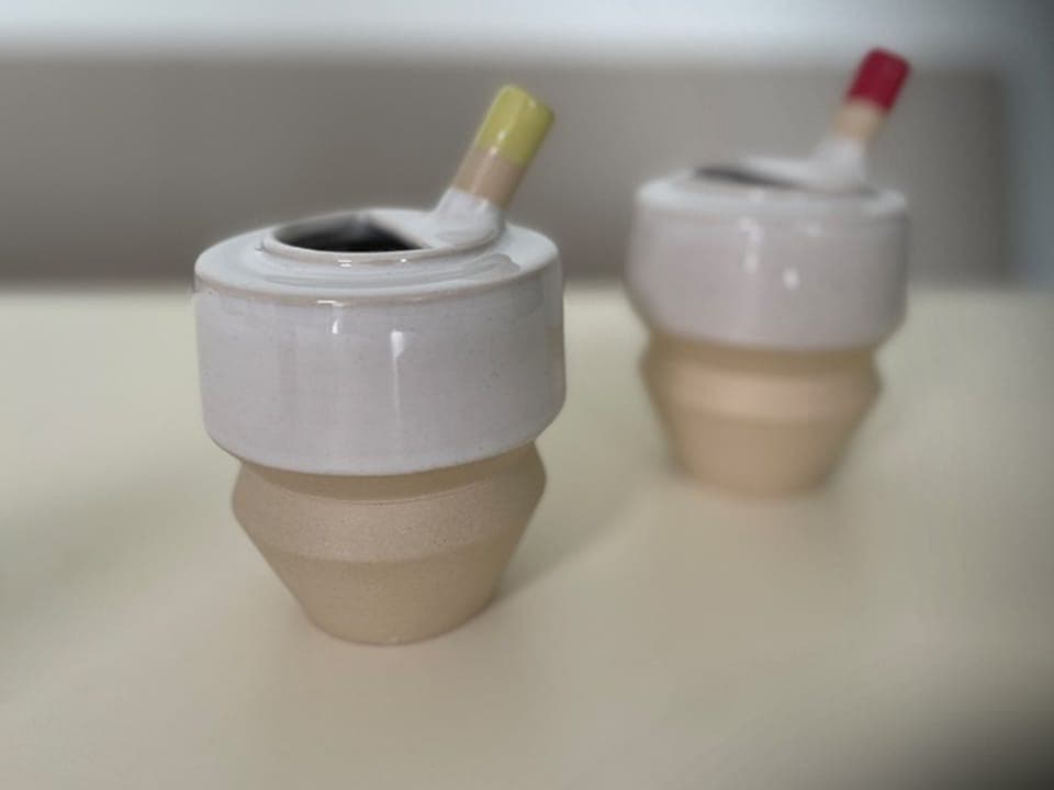 Zwei kleine Keramikbehälter mit Pinseln auf einer Oberfläche