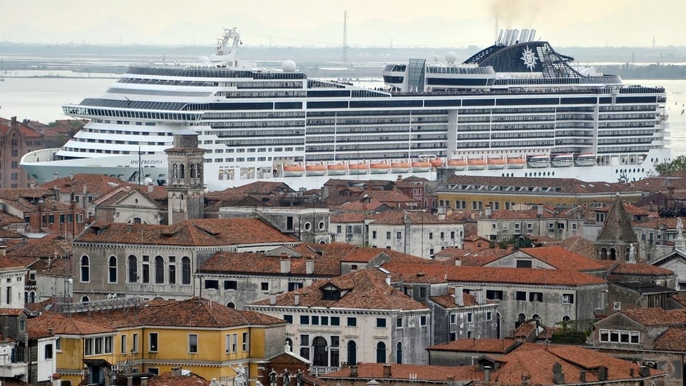 Ein Kreuzfahrtschiff im Hintergrund überragt die Stadtsilhouette von Venedig