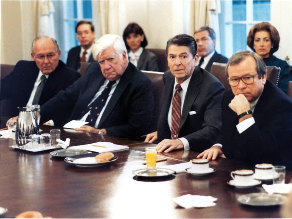 Sitzung des Weissen Hauses in den 1980er-Jahren. Mehrere Vertreter an Tisch versammelt.