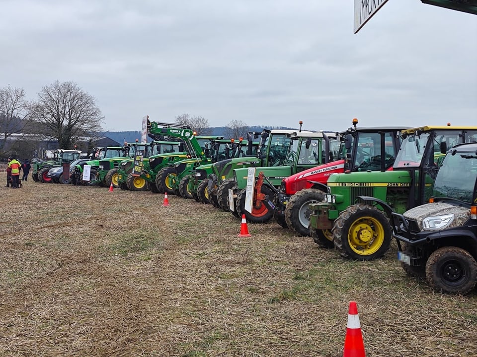Traktoren stehen in einer Reihe auf einem Feld.