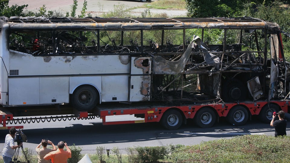 Ein ausgebrannter Bus auf einem LKW-Anhänger.