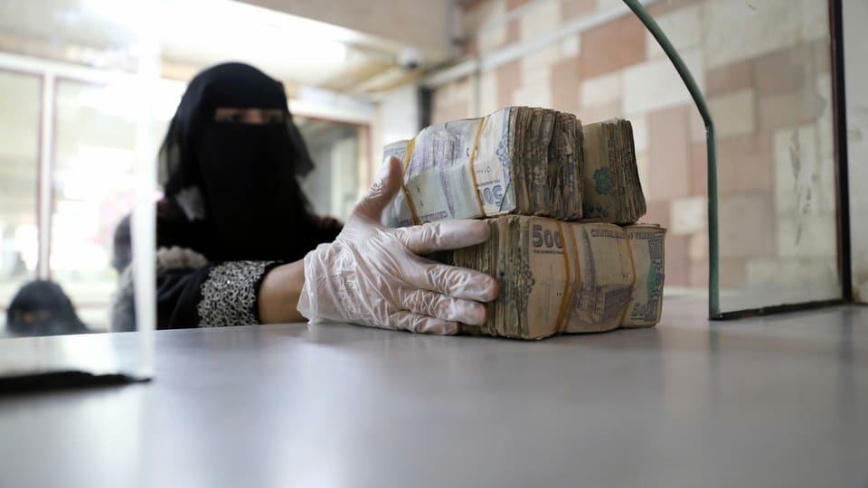 Eine verschleierte Frau bündelt Banknoten.