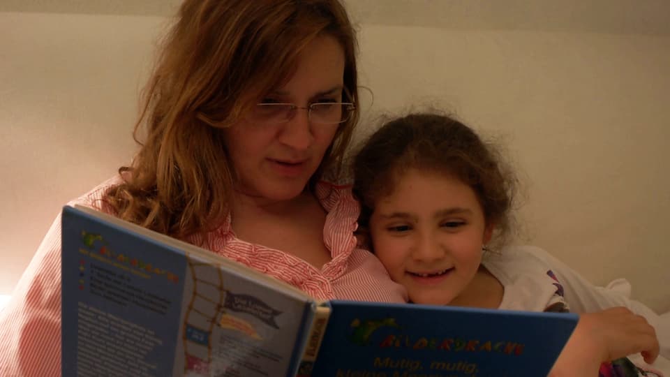 Eine Mutter liest zusammen mit ihrer Tochter ein Buch.