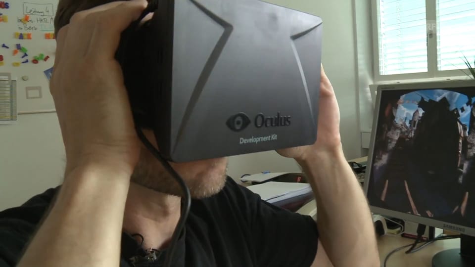 Ein Mann trägt eine Virtual-Reality-Brille die ein wenig so aussieht wie eine Skibrille mit Mini-iPad vorne dran.