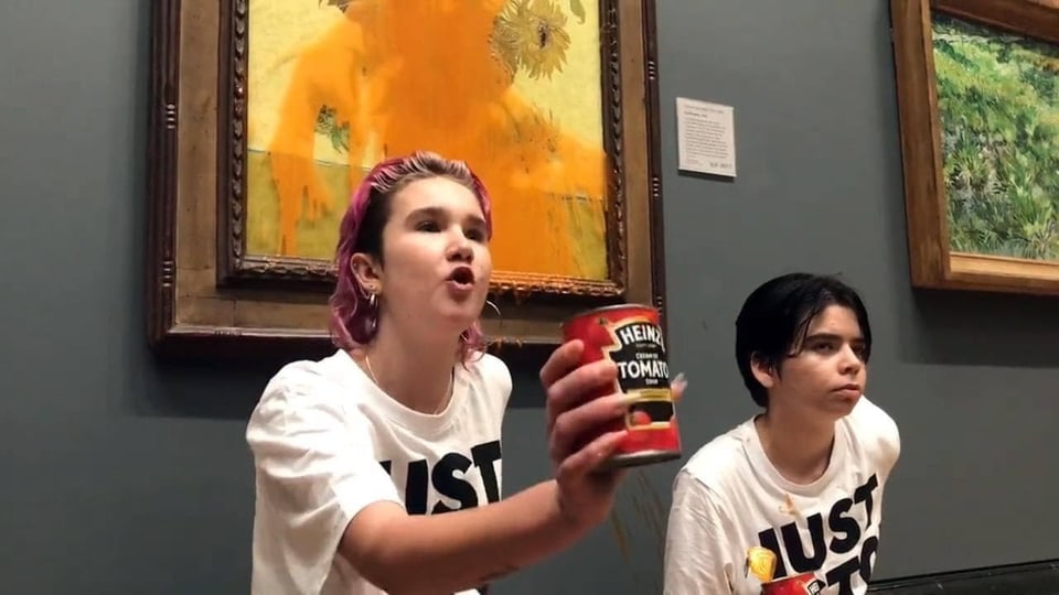 Aktivistinnen haben sich an eine Museumswand geklebt, über ihnen ein Bild von van Gogh mit Tomatensauce beschmiert