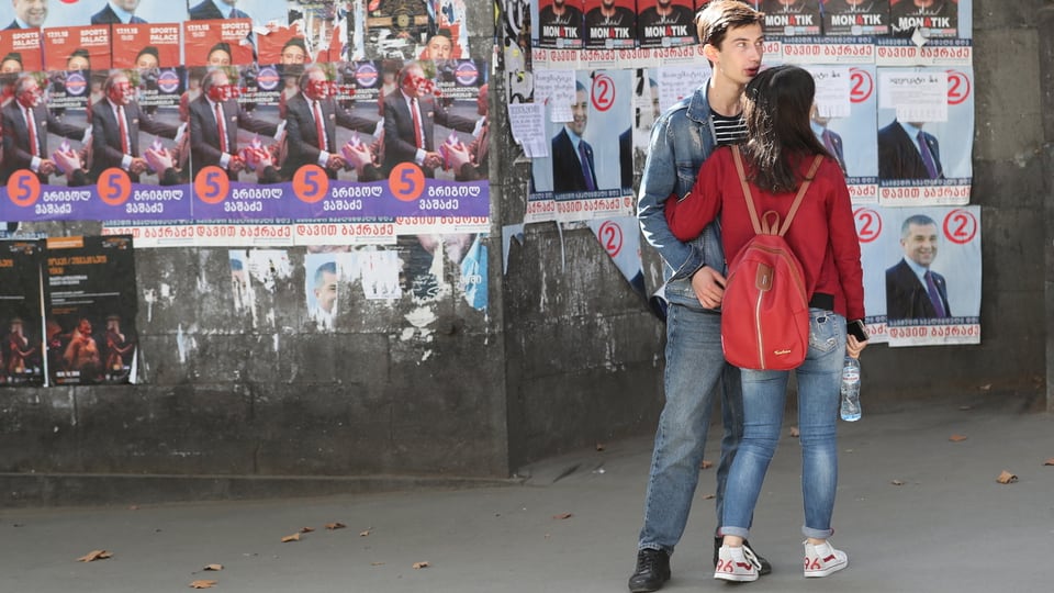 Junges Paar in Tiflis vor Wahlplakaten.