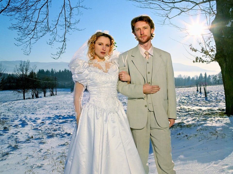 Eine Braut und ein Bräutigam auf einem Schneefeld.