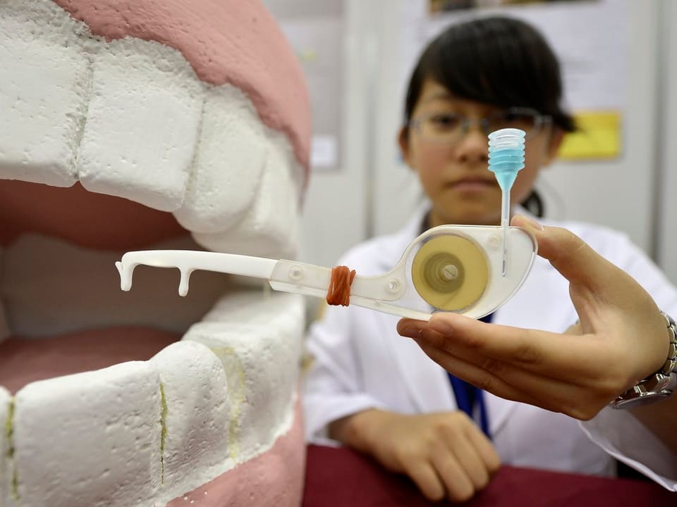 Jenny Che aus Taipei zeigt ihre ökologische Zahnseide an einem Zahnmodell.