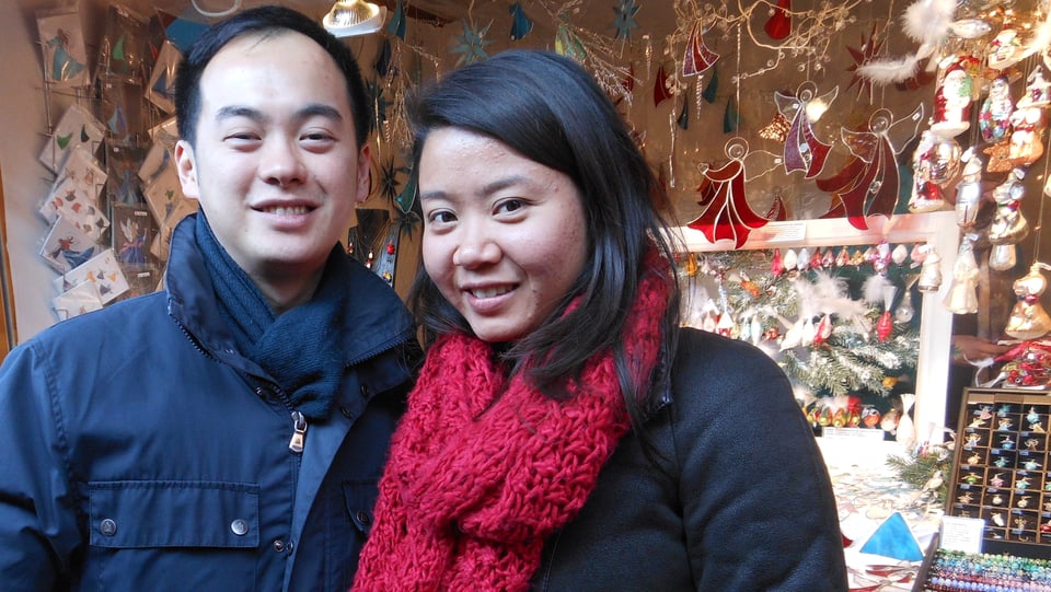 Japanisches Paar vor Stand an Weihnachtsmarkt. 