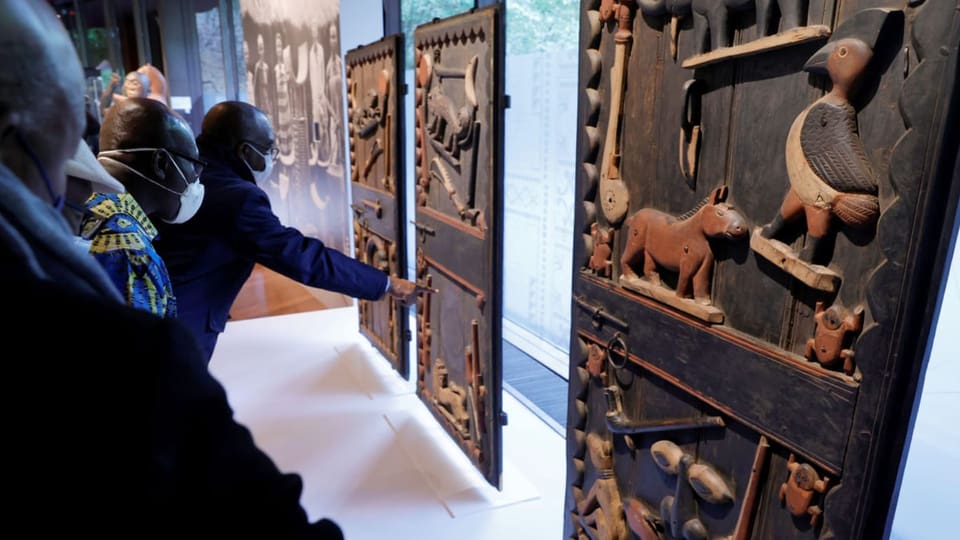 Museumsbesucher betrachten hölzerne historische Kunstwerke aus Benin.
