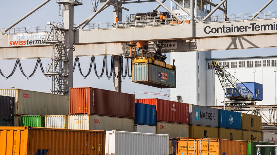 Am Container-Terminal Basel bei den Schweizer Rheinhäfen wird ein Schiffscontainer von einem Frachtschiff abgeladen.