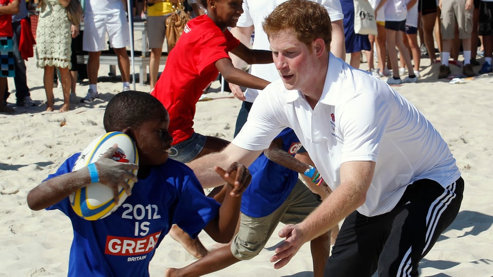 Prinz Harry spielt Rugby mit einem Kind.