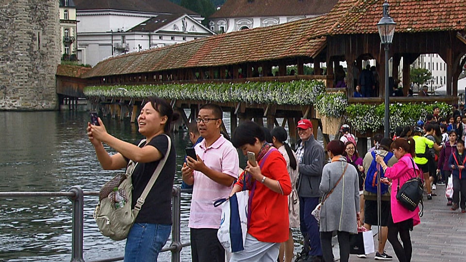 Asiatische Gäste fotografieren bei der Kapellbrücke in Luzern.