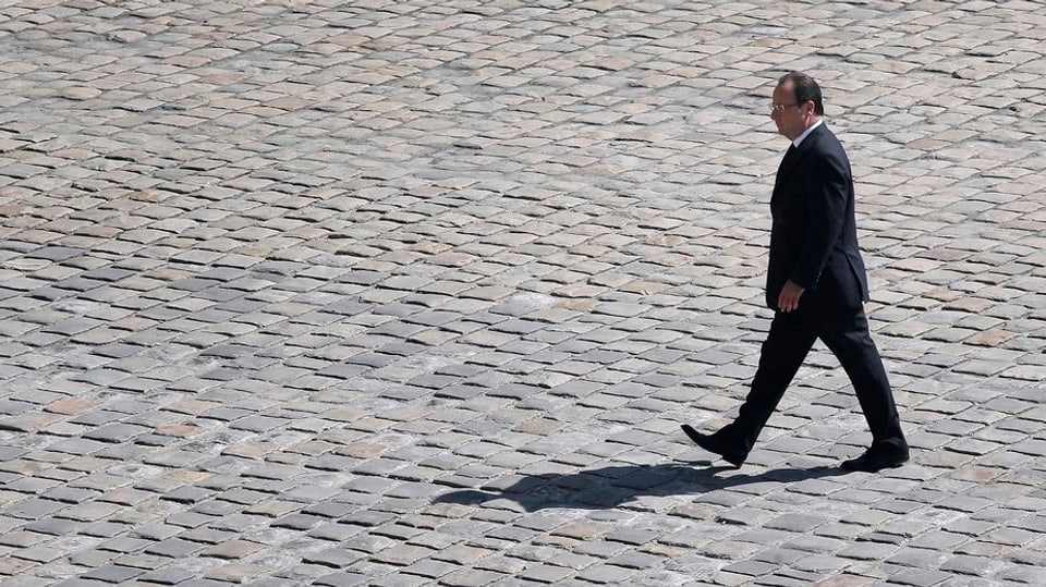 Der französische Präsident Hollande schreitet im Anzug über einen Platz
