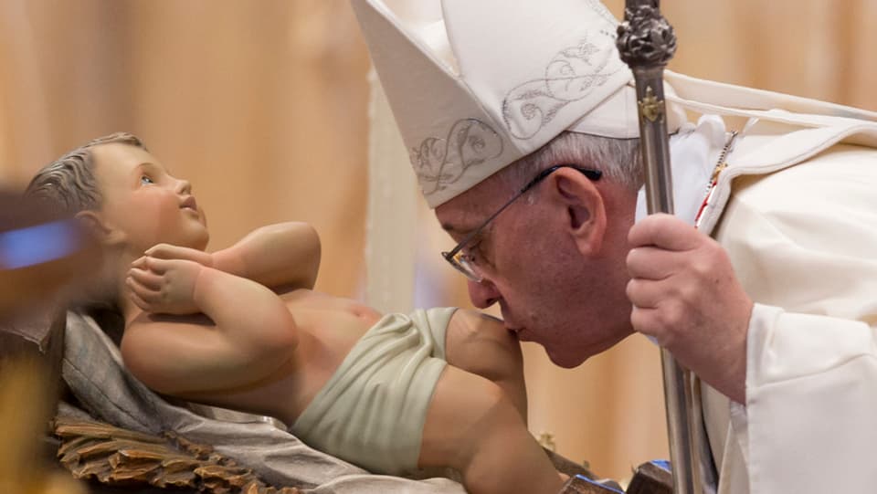 Papst Franziskus küsst ein Kind.