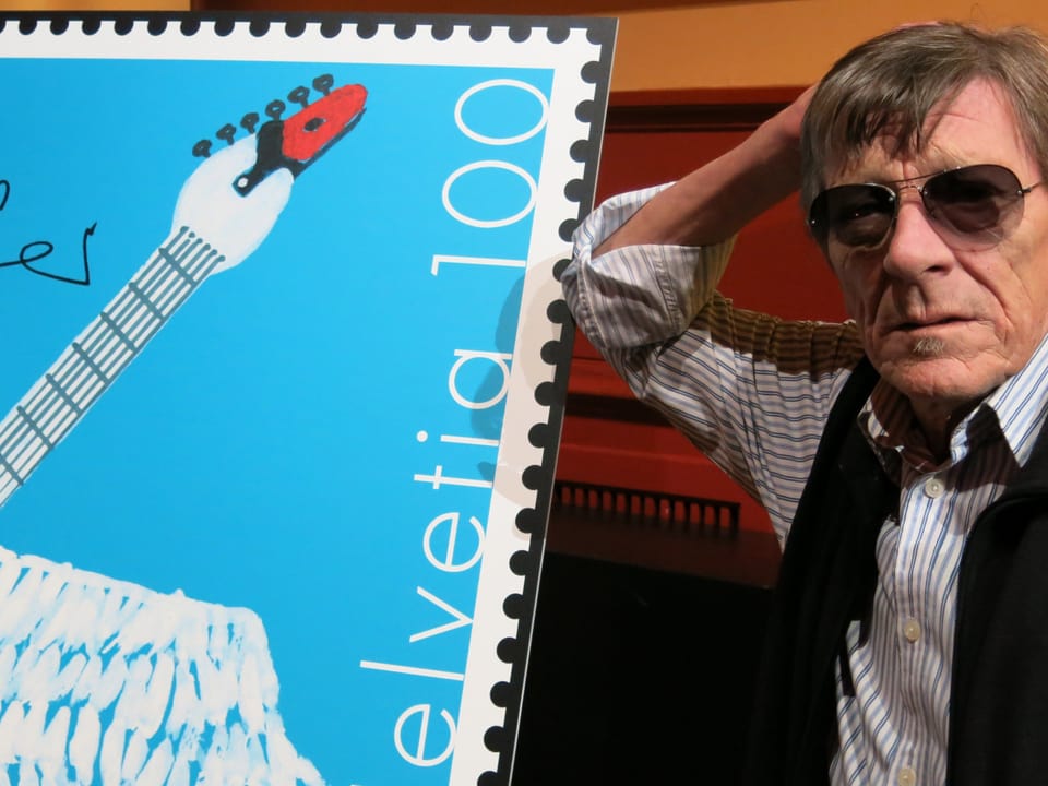 Mann mit Sonnenbrille steht neben übergrosser Briefmarke