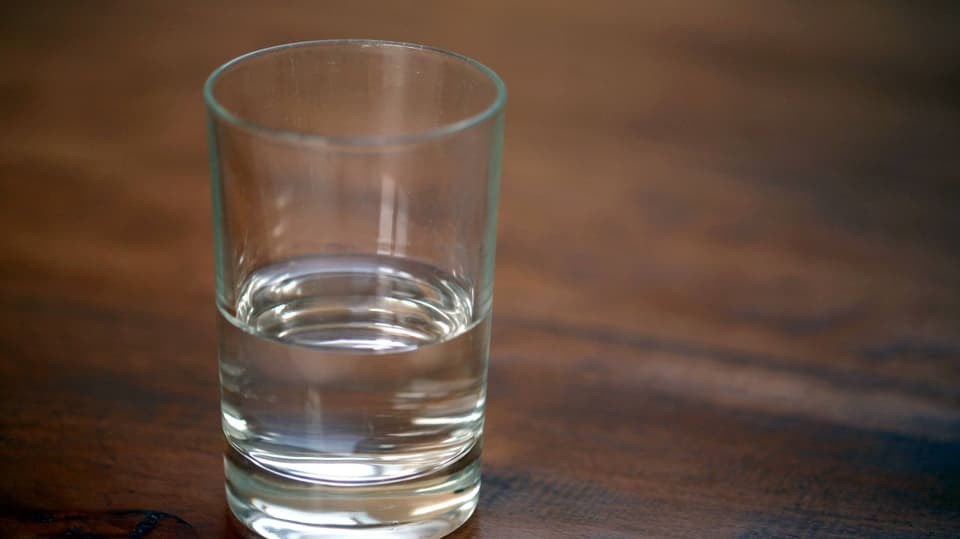 Ein halbvolles Glas steht auf einem Tisch.