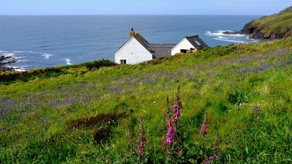 Ein Haus im Grünen, im Hintergrund das Meer.