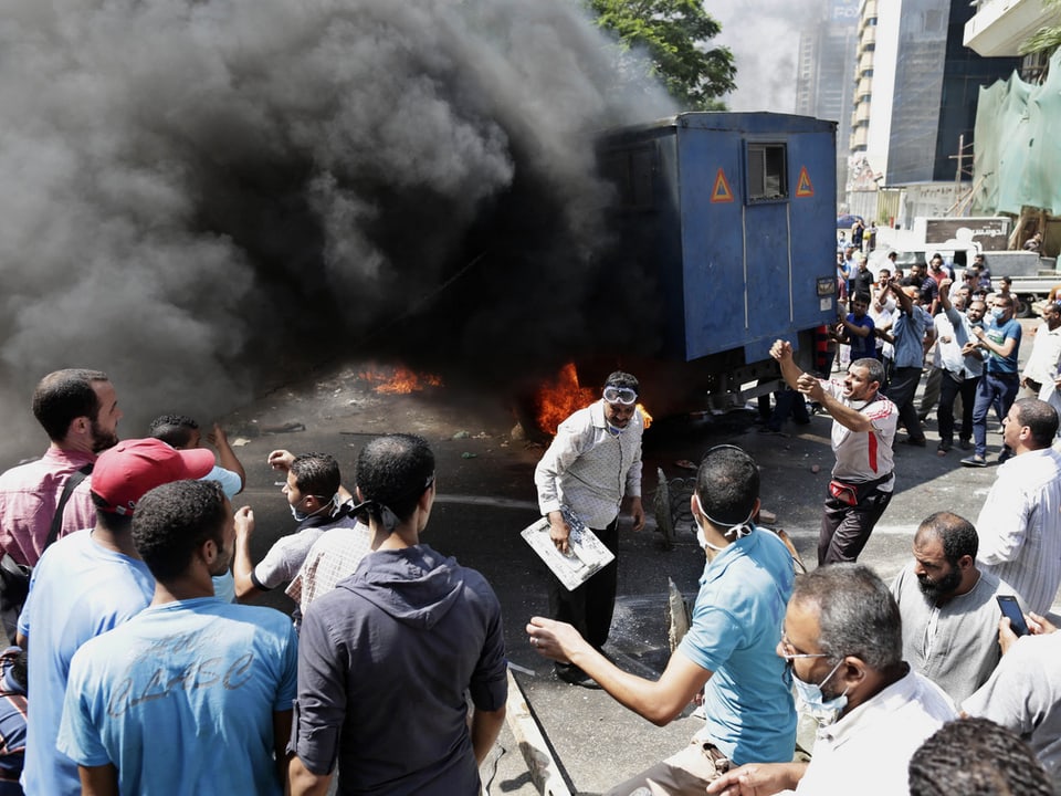 Protestierende Mursi-Anhänger haben einen Polizeiwagen angezündet und feiern ihre Aktion.