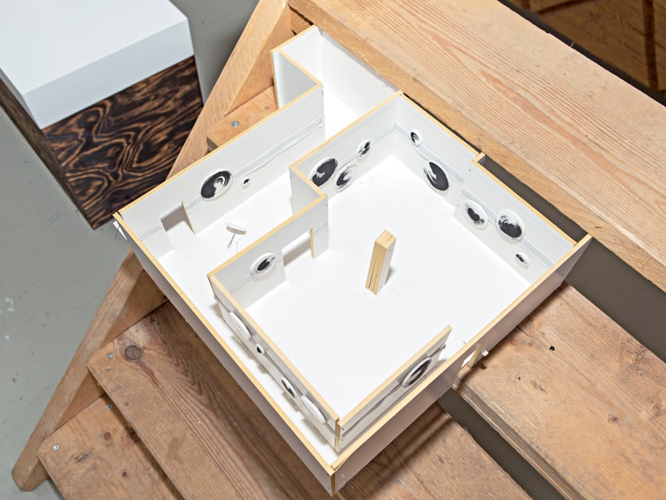 Das Modell eines Hauses steht auf einer Holztreppe.