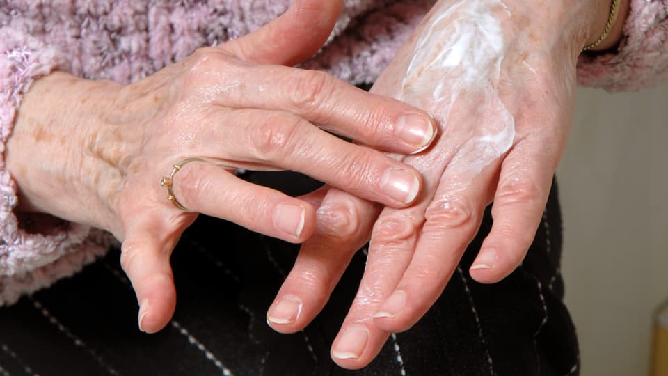 Ein Frau schmiert sich Handcreme auf die Hand