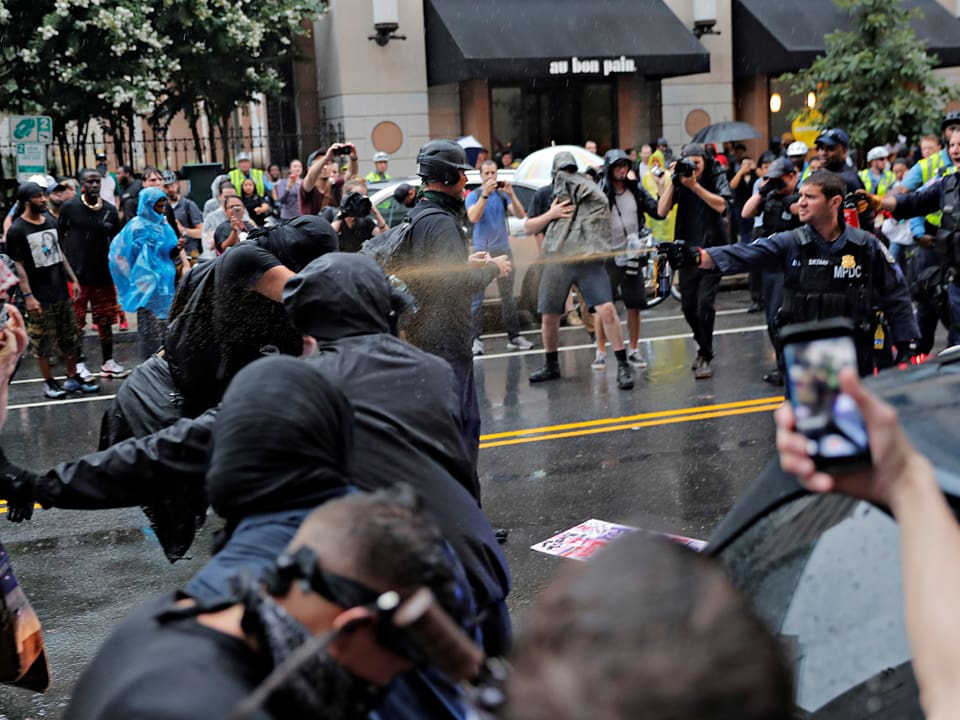 Ein Polizist schiesst mit einem Pfefferspray gegen einen Demonstranten.