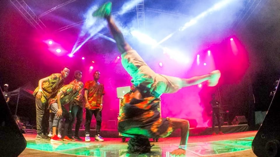 Ein junger Afrikaner vollführt auf einer Bühne einen Breakdance.