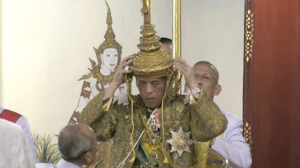 Mann setzt sich eine goldene Krone auf.