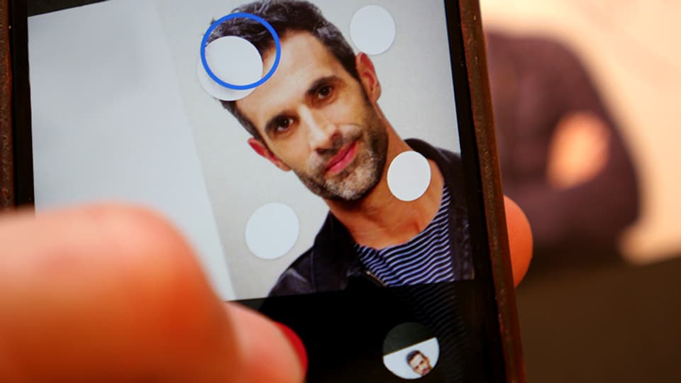 Das Porträit eines Mannes auf einem Handybildschirm.