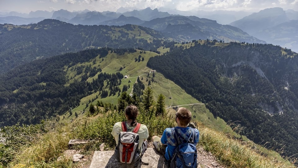 Zwei Wanderer sitzen auf Aussichtspunkt