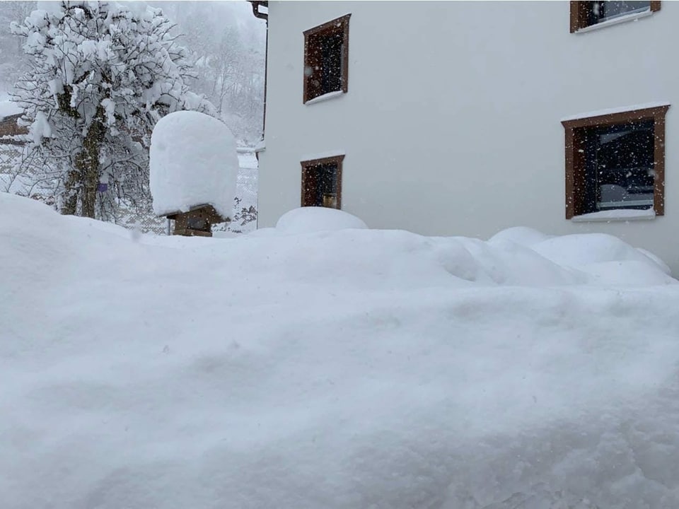 Schneeberge vor einer Häuserwand.