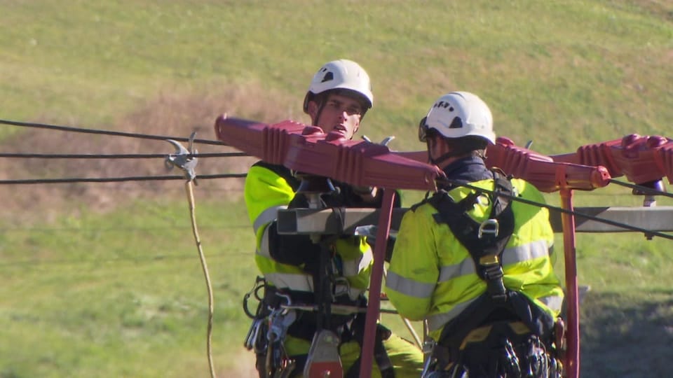 Zwei Arbeiter auf einem Strommast.