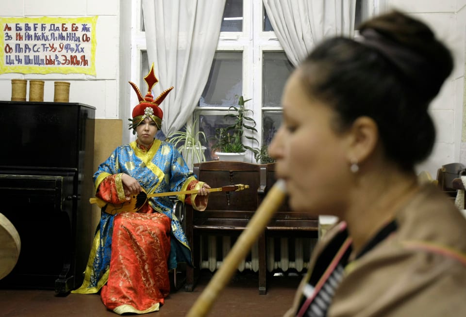Zwei junge Frauen in traditioneller Kleidung spielen Instrumente