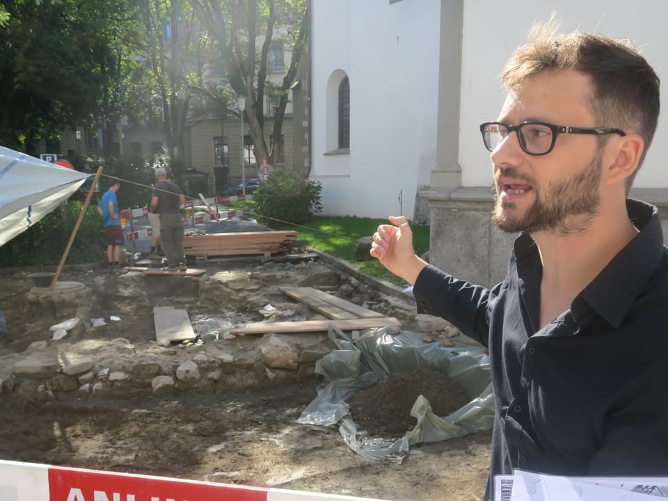 Ein Mann zeigt auf eine Grabungsstelle von Archäologen in der Stadt Luzern.