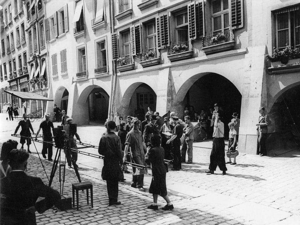 Filmtechniker beim Verlegen vom Kameraschienen in der Berner Innenstadt. Schaulustige stehen dabei.