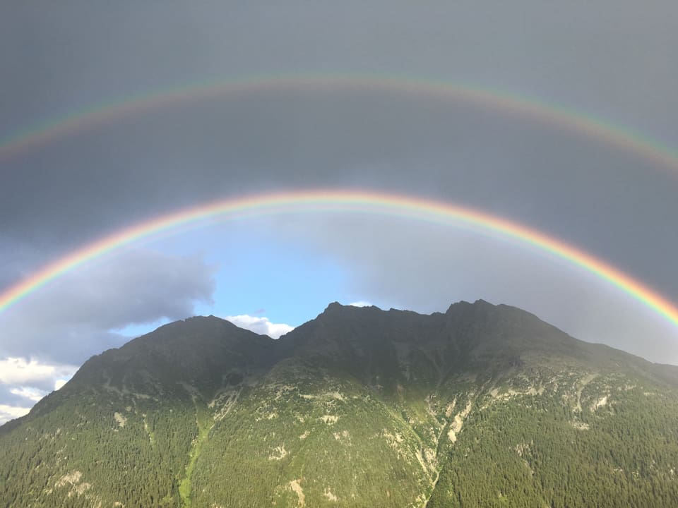 Zwei Regenbogen übereinander. Darunter die Berge und etwas blauer Himml.