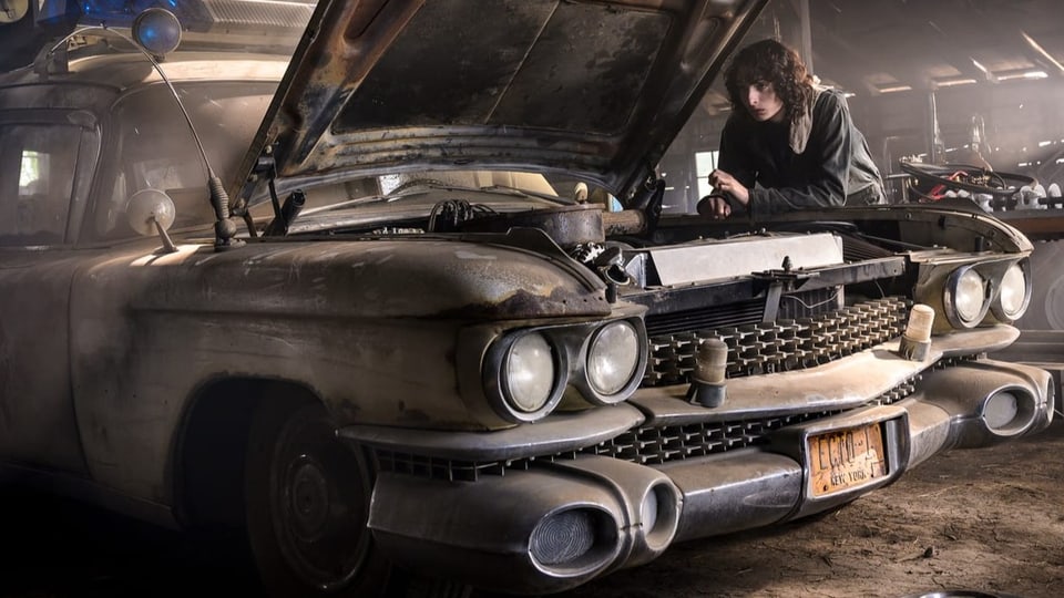 Finn Wolfhard blickt in die Motorhaube des Geisterjäger-Mobils Ecto-1.