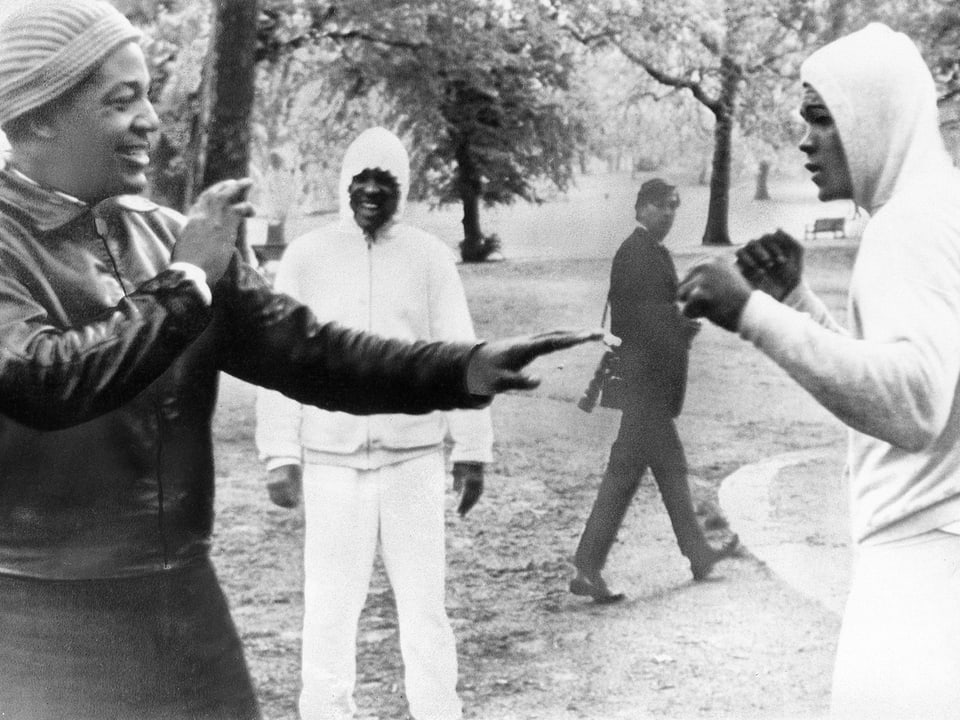 Schwarz-Weiss-Aufnahme von Muhammad Ali im Londoner Hyde Park 1964 zur Show boxend mit dem US-Football-Spieler Jim Brown