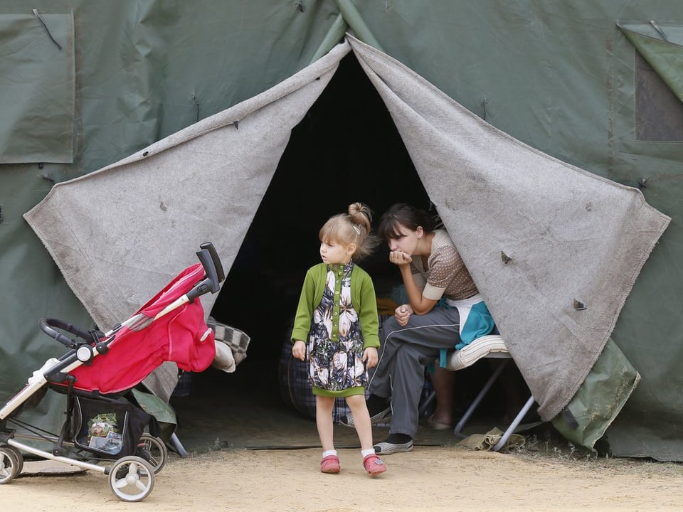 Eine Frau und ein Kind warten bei einem Zelt