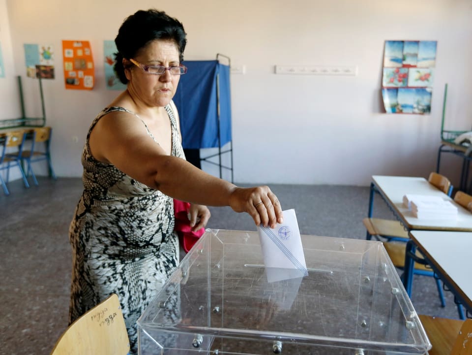 Eine Frau wirft ihren Stimmzettel in die Urne.