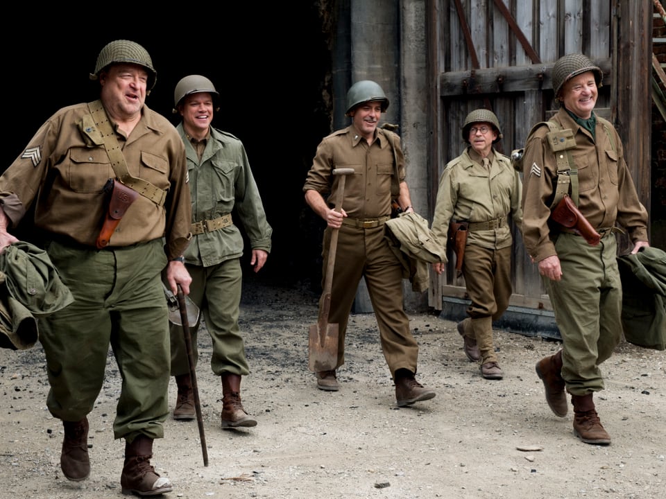 Filmszene: Die Schauspieler in Militäruniform gehen lachend nebeneinander her.