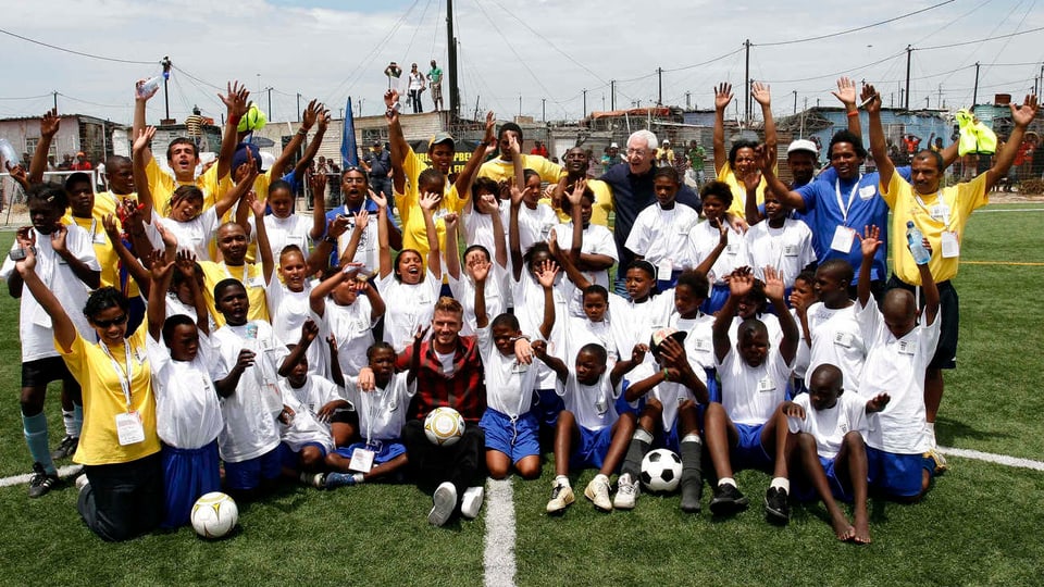 Eine Gruppe Kinder posiert mit David Beckham. 