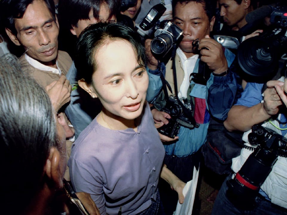 Aung San Suu Kyi bahnt sich vor ihrem Haus in Rangoon ihren Weg durch die Fotografenmassen.
